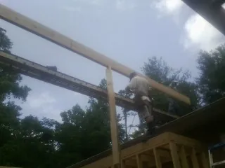 Carpenter setting a ridge beam over a new addition frame — Ice Dam Removal by Roofing Brothers in Castleton